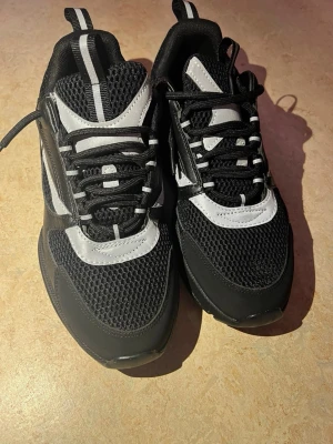 Svarta  sneakers - Snygga chunky sneakers i svart och vitt med mesh- och syntetdetaljer. Skorna har tjock sula, svarta och vita snören samt coola kontrastpaneler. Perfekta för dig som gillar streetwear och sportig stil.
