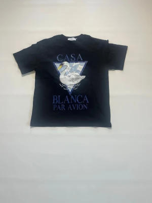 Svart Casablanca t-shirt storlek S - Cool svart t-shirt från Casablanca med tryck av en svan och texten 'Casa Blanca Par Avion' på framsidan. Klassisk passform med rund hals och korta ärmar. Perfekt för dig som gillar streetwear och unika prints. T-shirten är helt ny och aldrig buren och har storlek S