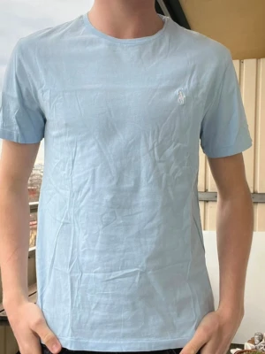 Ralph lauren T-shirt - Snygg ljusblå T-shirt från Ralph Lauren i mycket bra skick utan hål och slitningar! Storlek S Nypris~1000kr