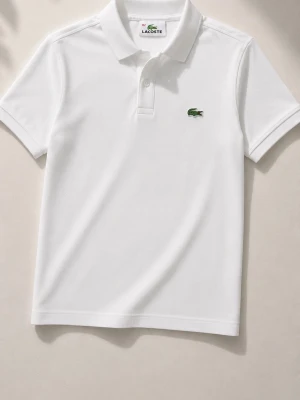 Vit pikétröja från Lacoste - Klassisk vit pikétröja från Lacoste med korta ärmar och krage. Tröjan har den ikoniska gröna krokodilloggan broderad på bröstet och är tillverkad i bomull. Perfekt för en stilren och sportig look. Knappast använd