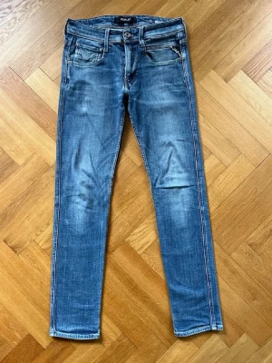 Replay Jeans - Snygga blå slim jeans från Replay med klassisk femficksdesign och slitna detaljer. Jeansen har normal midja och är tillverkade i stretchigt denim för extra komfort. Perfekta för en trendig och avslappnad stil.