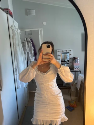 Vit omlottklänning med volang - Superfin vit klänning med omlottdesign och volangkant nertill. Endast använd på en avslutning💞