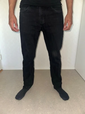Svarta raka jeans från 157 - Svarta jeans från 157 med klassisk femficksdesign och raka ben. Jeansen har normalhög midja och är tillverkade i ett mjukt denimtyg. Perfekta för en stilren och enkel look.