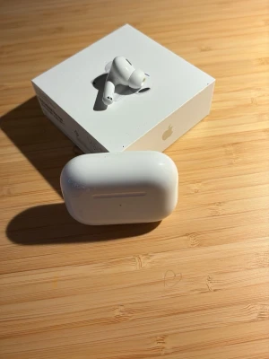 Apple AirPods Pro med laddningsetui - Säljer ett par vita Apple AirPods Pro med trådlöst laddningsetui. Hörlurarna har en stilren och kompakt design i blank plast och levereras i originalförpackning. Perfekta för dig som vill ha grymt ljud och smidig anslutning till din iPhone.