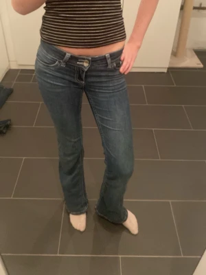 Blå bootcut jeans från Nelly - Säljer ett par klassiska blå bootcut jeans från Nelly. Jeansen har normal passform, låg midja och snygga detaljer på bakfickorna. Perfekta för dig som gillar en tidlös och avslappnad stil. Säljer dem för att jag har för många jeans.