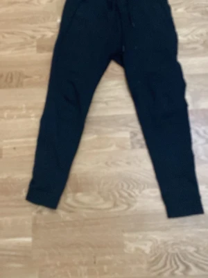 Svarta mjukisbyxor från Zara - Svarta mjukisbyxor från Zara med dragsko i midjan och muddar vid bensluten. Perfekta för en avslappnad stil och tillverkade i mjukt material som känns skönt mot huden. Klassisk passform och enkel design som funkar till det mesta.