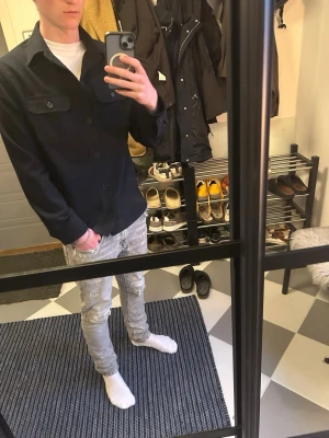 Marinblå/svart overshirt  - Säljer en marinblå/svart overshirt från Riley i Storlek s med klassisk krage och två bröstfickor med knappar. Skjortan har lång ärm och stängs med knappar framtill. Perfekt att bära öppen över en t-shirt för en avslappnad look.