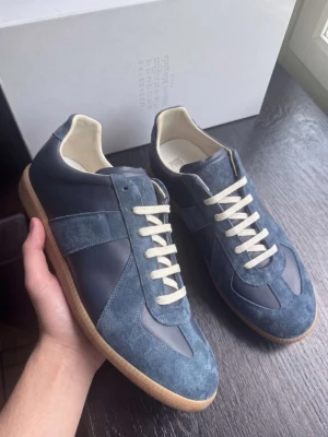 Maison Margiela – Navy | Strl 44 | Nyskick - Maison Margiela i navy — ikonisk fransk lyx med signatur vintage-inspirerad design och premium läder. Nyskick, luktar nytt och knappt använd. ✅ Originallåda ✅ Dustbag ✅ Skriv i DM för kvitto — vi håller det privat för att skydda köparens personliga information Storlek 44. Vi tar även emot byten och uppgraderingar. Vi reparerar, renoverar & rengör även skor — skriv i DM! 👟 📦 Spårad frakt, väl förpackad.