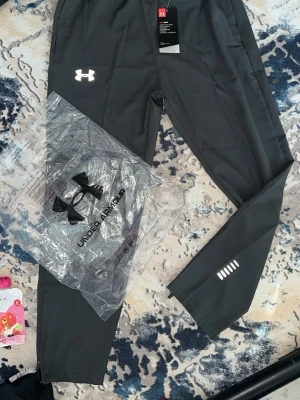 Under armour  - Gråa byxor från under armour med reflex. De är tunna så dom är perfekta för sommaren. Byxorna är aldrig använda.