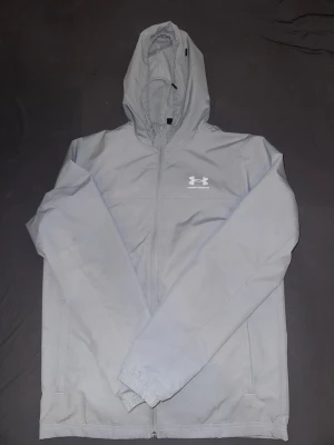 Under armour vindjacka  - En fin under armour windbreaker som är använd ett fåtal gånger. Jag säljer pga den va för liten på mig. Det finns några fläckar på jackan tyvärr vilket är varför jag sänker priset med nästan halva. Går enkelt att ta bort de ifall man kollar någon video men jag har ej orken för det.