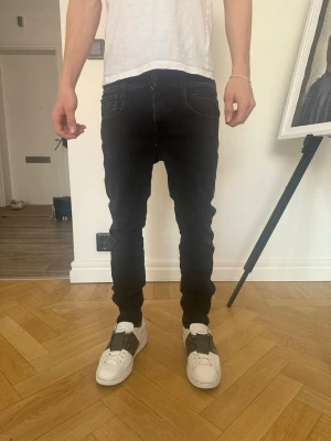 Svarta slim fit jeans från repaly  - Svarta slim fit jeans från repaly med klassisk femficksdesign och vita sömmar. Jeansen har låg midja och smal passform hela vägen ner. Perfekta för en stilren och modern look. Materialet är stretchigt för extra komfort. Coola detaljer på fickorna. Repaly ambass, nypris 1799