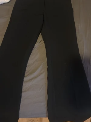 Svarta kostymbyxor från BikBok - Snygga svarta kostymbyxor från BikBok i storlek 34. Byxorna har en klassisk rak passform med lätt utsvängda ben och hög midja. Perfekta att styla med en crop top eller oversized skjorta. Materialet känns mjukt och följsamt.