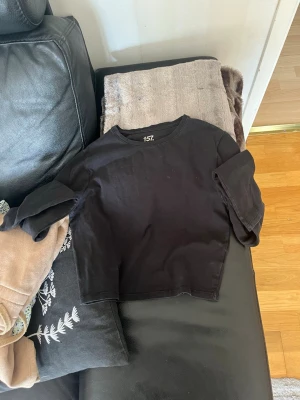 Svart croppad topp från 157 - Svart croppad topp från lager 157 med rund halsringning och långa ärmar . Enkel och stilren design som passar perfekt till jeans eller kjol. Tillverkad i mjuk bomull för en bekväm känsla.