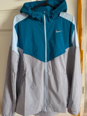 Nike Vindjacka  - Köpte jackan för 1400! Så kan inte gå ner så mycket i pris. Säljer redan den för 700 kr billigare. Jag har aldrig använt jackan, prislappen är kvar och jag säljer denna för att den inte passade mig. En ny vindjacka med fina färger, perfekt nu till sommar kvällarna. Jackan är tun och skön. Den här jackan passar dig som vill ha en fin stil och samtidigt mycket skön