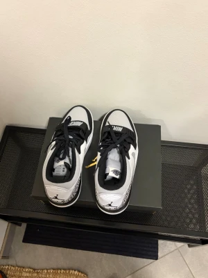Nike Air Jordan Legacy 312 Low vit/svart - Snygga Nike Air Jordan legacy 312 Low sneakers i vitt och svart med klassisk logga på tungan och hälen. Skorna har perforerad tå, svart snörning och en bred Nike-rem över vristen. Materialet är läder och textil, perfekt för dig som gillar streetstyle. Aldrig använda, box tillkommer