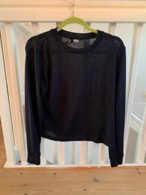 Svart stickad tröja från H&M - Snygg svart stickad tröja från H&M med rund halsringning och långa ärmar. Tröjan har en tunn och luftig stickning som gör den perfekt för lager-på-lager. Enkel och stilren design som passar till det mesta.