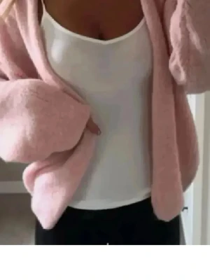 Ljusrosa oversized kofta - Mysig ljusrosa oversized kofta med långa ärmar och öppen front. Koftan har en fluffig och mjuk känsla, perfekt att slänga på sig över en topp. Enkel och stilren design som passar till många outfits.