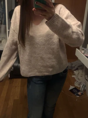 Beige stickad tröja med v-ringning - Mysig beige stickad tröja med v-ringad hals och långa ärmar. Helt oanvänd.