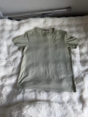 Ljusgrön basic t-shirt - En stilren ljusgrön t-shirt i klassisk modell med rund halsringning och korta ärmar. T-shirten har en liten diskret logga på bröstet och är tillverkad i mjuk bomull, perfekt för en avslappnad look.