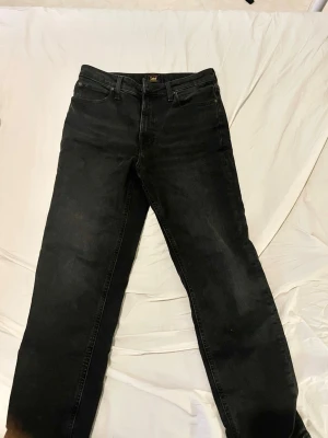 Svarta raka jeans från Lee - Säljer ett par svarta jeans från Lee med klassisk femficksdesign och raka ben. 