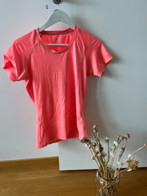 Korallrosa tränings-tshirt Pro Touch - Snygg korallrosa tränings-tshirt från Pro Touch. T-shirten har korta ärmar, rund halsringning och är tillverkad i ett lätt och snabbtorkande funktionsmaterial. Perfekt för löpning, gym eller annan träning.