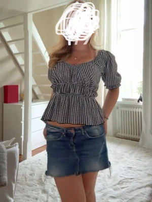 Svartvit rutig blus - Superfin svartvit rutig blus med puffärmar och smock i midjan. Söt v-ringning och volang nertill ger en romantisk vibe. Perfekt att styla med jeans eller kjol för en trendig look.