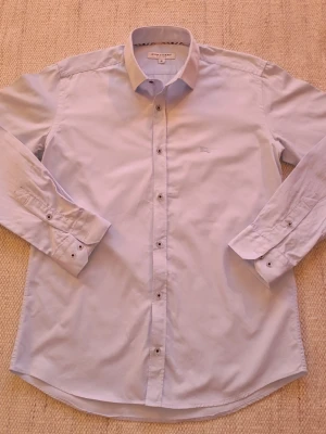 Burberry skjorta  - Klassisk snygg ljusblå skjorta från Burberry med lång ärm och knappar framtill. Skjortan har en stilren design med liten broderad logga på bröstet och är tillverkad i bomull.