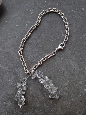Armband med stenhängen - Armband med grov silverfärgad kedja (ganska säker på att den är sterling 925 silver för den har gått igenom allt under flertal år och är fortfarande fin) och två hängen av oregelbundna, genomskinliga stenar. Kedjan har ett robust klolås och stenarna ger en unik och edgy känsla. Stenarna sitter på metall som går att justera och böja efter vad du vill. Tror det en gång i tiden satt en liten silver grej där det stod ”SNÖ” på som fallit bort
