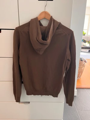 Brun hoodie från Stenströms - Snygg brun hoodie från Stenströms i storlek M. Hoodien har dragkedja framtill, ribbade muddar och är tillverkad i ett mjukt stickat material. Perfekt för en avslappnad och stilren look.