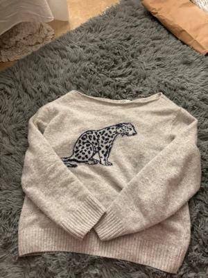 Ljusgrå stickad tröja med leopard - Använt en del, nopprig/luddig. Storlek ONE SIZE skulle nog passa mellan XXS-S och personer som är under 170cm. Kan nog krympt lite i tvätten då jag inte visste den skulle handtvättas istället