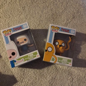 Adventure time funko pops - Adventure Time Funko Pop – Finn & Jake Säljer två äldre och eftertraktade Funko Pop från Adventure Time: * Finn #32 * Jake #33 Båda kommer med originalbox och passar perfekt för samlare!!. Figurerna är vaulted/utgångna ur produktion vilket gör dem svårare att hitta idag. Skick enligt bilder. Deras pris ligger på över 2000 men på grund av att boxarna har öppnats av tidigare ägare är priset nedsänkt markant, boxarnas struktur är inte skadat!! Pris: 1850 kr för båda Kan säljas separat vid rätt bud.