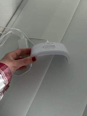 Depend Gel iQ UV/LED-lampa - Praktisk vit UV/LED-lampa från Depend Gel iQ, perfekt för att härda gelélack hemma. Lampan har en smidig bågformad design och ansluts med medföljande sladd och adapter. Passar till nagelvård och ger salongskänsla direkt i hemmet.