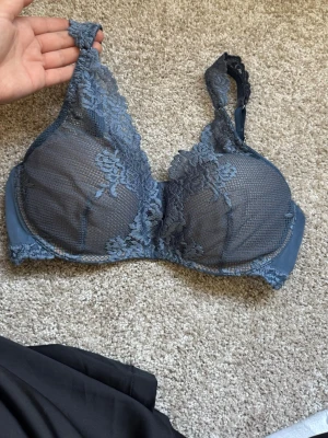 Blå spets-bh med blommönster - Snygg blå bh med vacker spets och blommönster. Bh:n har bygel och breda axelband för extra stöd. Materialet är en kombination av mesh och spets som ger en feminin och elegant look.