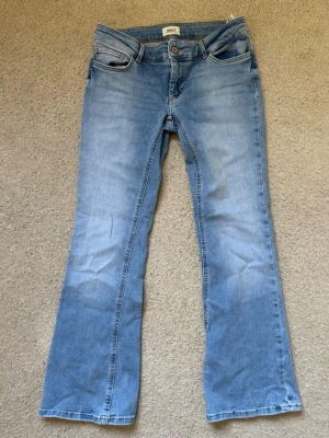 Ljusblå lågmidjade bootcut jeans från ONLY - Ljusblå jeans från ONLY med bootcut passform. Jeansen har en snyg. Använda mycket sparsamt och superfina nu till sommaren!
