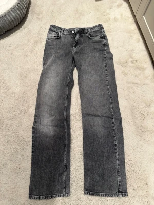 Grå raka jeans med vintagekänsla från Bikbok - Säljer ett par grå jeans med rak passform och klassisk femficksdesign. Jeansen har en snygg tvättad look och normal midja. Perfekta för dig som gillar en avslappnad och tidlös stil. Materialet är denim i bomull. Rensade från min garderob, använda några gånger men är i mycket bra skick :)