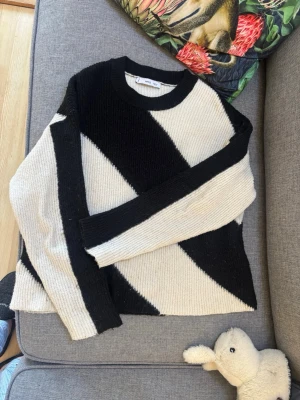 Svartvit stickad tröja från Monki - Säljer en cool stickad tröja från Mango med breda diagonala ränder i svart och vitt. Tröjan har rund halsringning och långa ärmar. Perfekt för dig som gillar grafiska mönster och vill sticka ut lite extra.