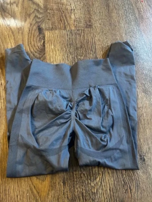 Grå scrunch leggings med hög midja - Snygga grå leggings med scrunch-detalj bak och hög midja. De är sömlösa och har en tight passform som framhäver formerna. Perfekta för gymmet eller chill. Materialet känns stretchigt och mjukt mot huden.
