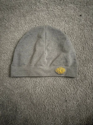 Grå basic mössa i mjukt tyg - En stilren grå mössa i mjukt och stretchigt tyg. Enkel design utan synliga loggor eller detaljer, perfekt för dig som gillar en clean look. Passar bra till både streetwear och casual outfits.