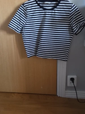 Randig t-shirt från Zara - Snygg randig t-shirt från Zara i blå och vitt. Klassisk modell med korta ärmar och rund halsringning. Perfekt till jeans eller kjol för en stilren look. Tillverkad i mjuk bomull som känns skön mot huden.