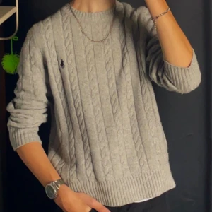 Grå stickad tröja från Polo Ralph Lauren - Säljer en klassisk grå kabelstickad tröja från Polo Ralph Lauren. Perfekt för en stilren och avslappnad look. Knappt använd och i nytt skick. Skriv för fler bilder och pris kan diskuteras.