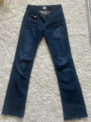 Mörkblå bootcut jeans från ONLY - Säljer ett par mörkblå bootcut jeans från ONLY med klassiska fem fickor och snygga kopparfärgade knappar. Jeansen har en lätt utsvängd passform och kontrastsömmar. Perfekta för dig som gillar en tidlös och avslappnad stil.