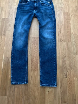 Blå tajta jeans från Replay - Säljer ett par slim blå jeans från Replay med tajt passform. Jeansen har modellen Wallys vilket innebär att de är super slim. Jeansen har snygg tvätt med lätt slitning och kontrastsömmar. Perfekta till en schysst stil och tillverkade i bomull för en nice känsla. Köpta nya från boozt, utan defekter!