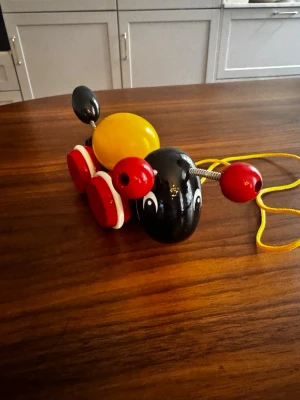 BRIO dragleksak i trä, myra - Klassisk dragleksak från BRIO i form av en myra. Tillverkad i trä med svart huvud och kropp, gul rygg, röda antenner och hjul med vita detaljer. Leksaken har ett gult snöre för att dra den efter sig. Perfekt för yngre barn som gillar att leka och röra på sig.