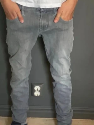 Grå skinny jeans från Jacob Cohën - Snygga grå jeans från Jacob Cohën i skinny fit. Byxorna har klassisk femficksdesign, silverfärgad knapp med J-logga och exklusiva detaljer på insidan. Materialmix med bomull och stretch för en mjuk känsla och bra passform. Stl 27.   73cm benlängd  Midja 36” Ca 170 när bilden togs