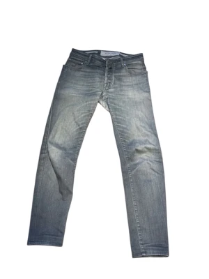 Grå tvättade jeans från Jacob Cohën - Snygga grå jeans från Jacob Cohën med tvättad look och raka ben. Klassisk femficksmodell med dragkedja och knapp. Jeansen har en cool, sliten finish och är tillverkade i bomull för en bekväm känsla.