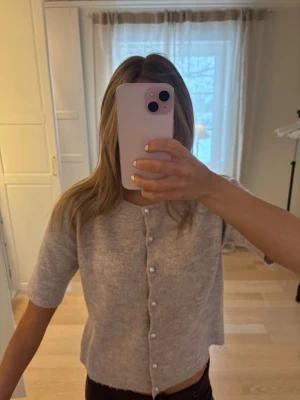 Beige stickad kofta med pärlknappar - Supersöt beige stickad kofta med korta ärmar och pärlknappar framtill. Mjuk och skön, passar till allt. Säljer pgr av att den är lite för liten💗