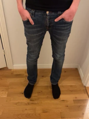 Blå slim fit jeans med slitningar - Säljer ett par blå slim fit jeans med snygga slitningar och tvättade detaljer. Jeansen har klassisk femficksdesign och kontrastsömmar på bakfickorna. Perfekta för en avslappnad och trendig look. Skriv för mer info 