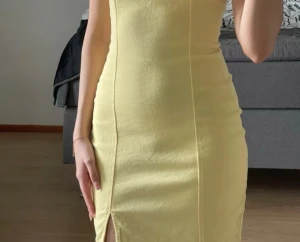 Gul kort klänning med slits - Snygg gul kort klänning med smala axelband och slits framtill. Figurnära passform som framhäver midjan. Perfekt för varma dagar och somriga tillfällen. 