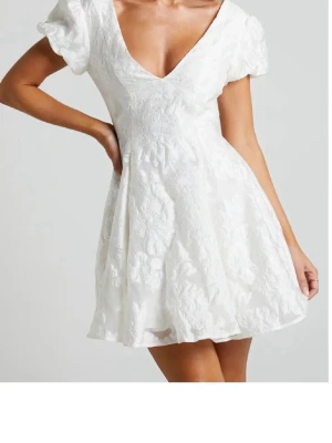 Vit kort klänning med puffärm - Superfin vit kort klänning med v-ringning, puffärmar och öppen rygg. Klänningen har ett broderat blommönster och volangig kjol som ger en romantisk vibe. Perfekt för sommarens alla tillfällen! Pris kappen kvar! Köpte av en tjej här på Plick men har hittat en annan klänning till studenten!💓