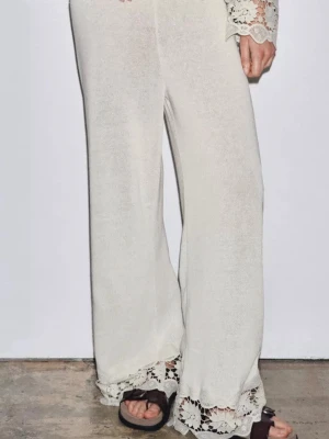 Vida linnebyxor med spetsdetaljer - Säljer ett par ljusa, vida linnebyxor med snygga virkade spetsdetaljer längst ner vid bensluten. Byxorna har en avslappnad passform och är perfekta för en chill och trendig look. Materialet är tunt och luftigt linne som känns skönt mot huden.